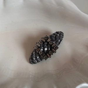 Detail of elegant black fabric hair clip featuring sparkling grey rhinestones and silver accents