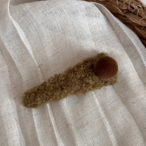 Détail d'une pince à cheveux triangulaire en peluche marron avec une texture douce et chaude