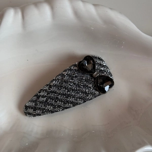 Detail of tweed fabric hair clip featuring sparkling heart-shaped rhinestones decoration