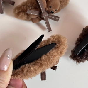 Detail of plush bear hair clip featuring brown faux fur texture and a cute bow