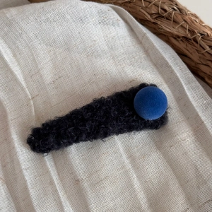 Détail de la pince à cheveux en peluche noire avec boule en velours bleu roi