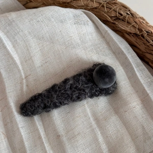 Détail de la pince à cheveux en tricot gris foncé avec boule en peluche pour l'hiver