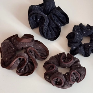 Detailed macro view of polka dot knitted scrunchies with satin ruffled edges in dark tones