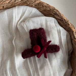 Dettaglio del fermaglio per capelli con fiocco in velluto rosso scuro e perle floccate morbide