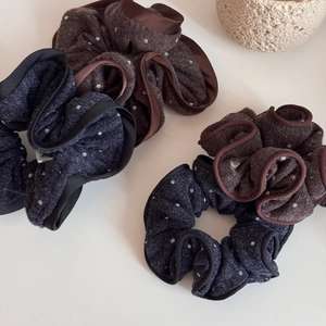 Detailed texture of polka dot knit scrunchies in navy blue and brown with ruffled edges