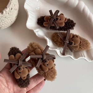 Brown plush bear and bow hair clips set on a white decorative tray for women