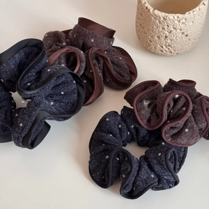 Close-up of four knitted polka dot scrunchies in navy blue and dark brown colors