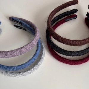 Detail of six colorful knitted plush headbands with handmade labels on white background