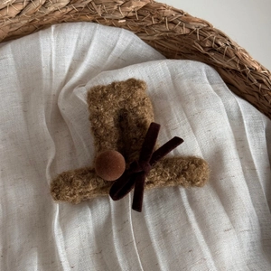 Dettaglio di un fermaglio per capelli marrone a forma di cappello con fiocco di velluto