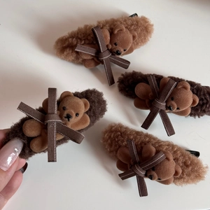 Detail view of plush bear hair clips with velvet bow accents in warm brown tones