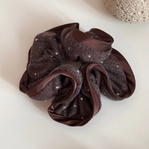 Detailed texture of brown polka dot knitted scrunchie with satin edge stitching