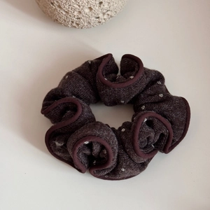 Close-up of brown knit polka dot scrunchie with ruffled edges and fine stitch details
