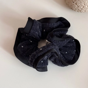 Close-up of navy blue polka dot knitted scrunchie with elegant black satin edge details
