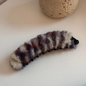 Dettaglio della molletta a banana in peluche con trame di pelliccia viola e marrone calde
