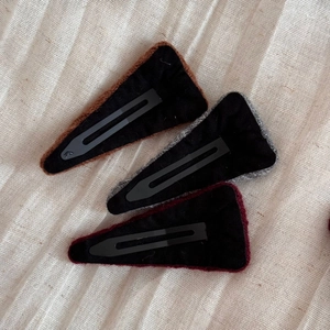 Detail of three knitted triangle hair clips showing the non-slip black felt backing