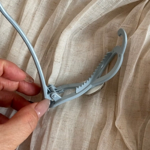 Détail de la pince à cheveux bleu clair avec mécanisme à ressort et design antidérapant