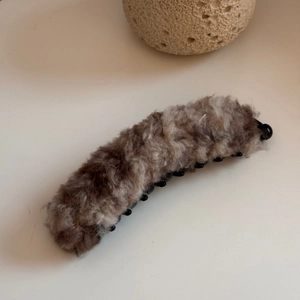 Dettaglio del fermaglio a banana in peluche marrone con trama in morbida ecopelliccia