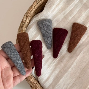 Close-up of knit wool hair clips in vintage grey brown and red colors set in a basket