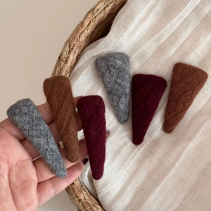 Detail of knitted triangular hair clips with striped texture in grey brown and dark red