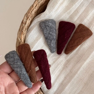 Detailed close-up of chunky knit triangular hair clips in grey, brown, and burgundy
