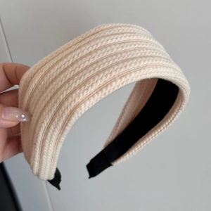 Detalle de diadema de punto beige con textura de trenzas gruesas y forro interior negro
