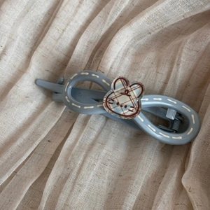 Détail d'une pince à cheveux bleue à motif infini avec lapin à carreaux et coutures