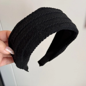 Detalle de diadema ancha de punto trenzado negro con textura gruesa y acolchado vintage