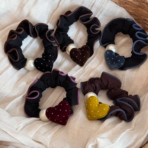 Dettaglio di cinque elastici per capelli con cuori in velluto e perle su tessuto