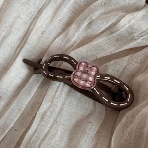 Détail d'une pince à cheveux lapin marron avec motif à carreaux rose sur lin doux