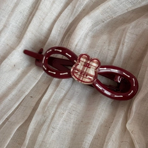 Détail d'une barrette à nœud bordeaux avec un motif de lapin à carreaux sur tissu doux