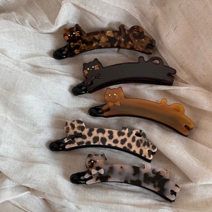 Detailed flat lay of five acetate cat-shaped banana hair clips in various marble patterns
