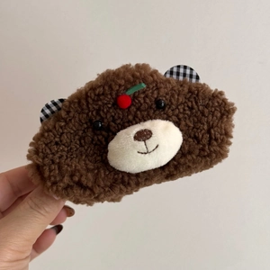 Détail de la pince à cheveux ours en peluche marron avec cerise et oreilles à carreaux