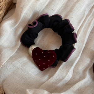 Dettaglio scrunchie nero con motivo a cuore floccato rosso e decorazione con perla