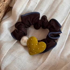Dettaglio di cuore in velluto e perla su elastico marrone con bordo blu a volant