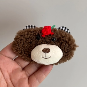Gros plan d'une pince à cheveux ours en peluche avec laine d'agneau et détail de fleur