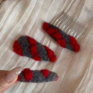 Détail d'un ensemble de barrettes en laine tricotée rouge et grise avec peigne en métal