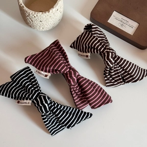 Detailed view of striped fabric bow hair clips in three neutral colors on a wooden tray