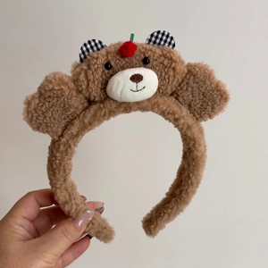Détail d'une pince à cheveux ours en peluche marron avec oreilles à carreaux élégantes