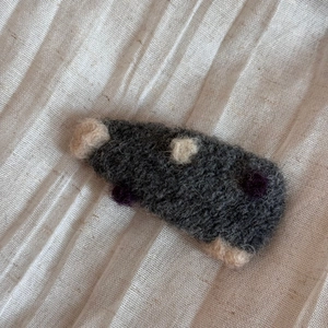 Détail d'une pince à cheveux en feutre faite main avec texture laineuse et pois colorés