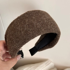 Détail d'un serre-tête large en peluche marron montrant la texture douce de la fourrure