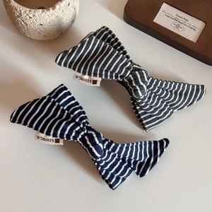 Detailed view of striped fabric bow hair clips in black and navy on a rustic table