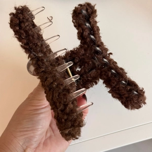 Close-up of brown plush hair claw clip showing H-shaped design and soft faux fur texture