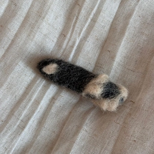Détail d'une pince à cheveux en feutre de laine douce avec des fibres noires et blanches