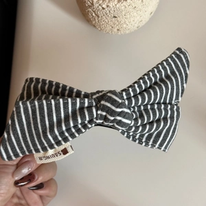 Macro shot of grey striped fabric bow hair clip featuring a woven brand side label