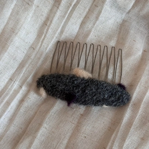 Gros plan sur un peigne en feutre de laine gris foncé avec des dents en métal argenté