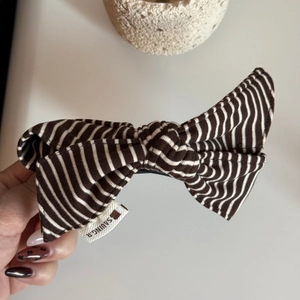 Close-up of brown and white striped fabric bow hair clip with durable metal spring clip