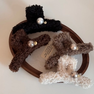 Elegant plush hair claw clips set with large pearls in four earthy colors in a wooden tray