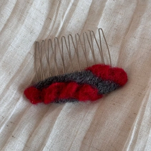 Détail d'un peigne à cheveux en laine feutrée bicolore rouge et gris sur métal
