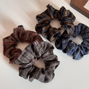 Close-up of four vintage plaid scrunchies in autumn colors with detailed fabric texture