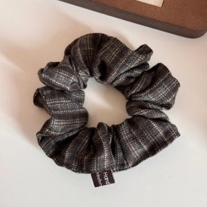 Close-up of vintage dark grey plaid wool scrunchie with detailed woven textile label
